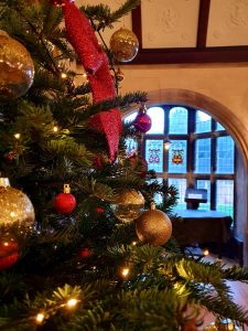 Christmas tree with gold and red decorations in front of a stained glass window