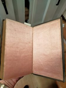 The interior of an 18th century book, lined in beautiful, shiny salmon pink satin.