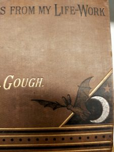 A tiny little bat in front of a crescent moon, on the cover of a late 19th-century book